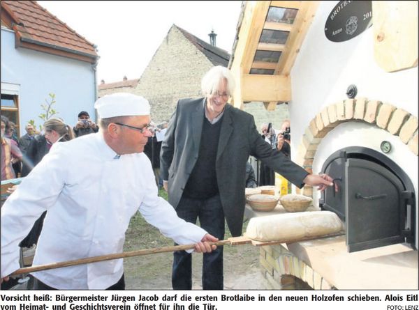Vorsicht heiß: Bürgermeister Jürgen Jacob darf die ersten Brotlaibe in den neuen Holzofen schieben. Alois Eitl vom Heimat- und Geschichtsverein öffnet für ihn die Tür. | Quelle: DIE RHEINPFALZ - Ludwigshafener Rundschau - 15. Oktober 2012 – Text: Jochen Willner | Foto: Lenz | Mit freundlicher Genehmigung der RHEINPFALZ Verlag und Druckerei GmbH & Co. KG in Ludwigshafen.